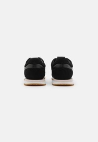 Black athletic shoes featuring a mix of suede and synthetic materials, with a rubber sole and contrasting white midsole.