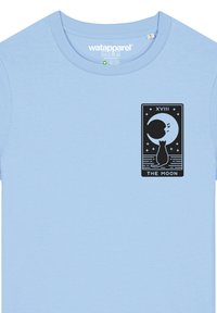 T-shirt en coton bleu clair avec un motif graphique noir représentant un chat et une lune, accompagné du texte "XVIII LA LUNE" à l'intérieur d'un design rectangulaire.