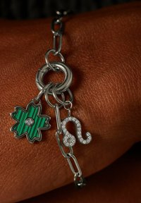 Zilveren kettingarmband met een groen gestreepte bloemenhanger met een strass-steentje en een sprankelende zilveren boogschutter-symboolhanger.
