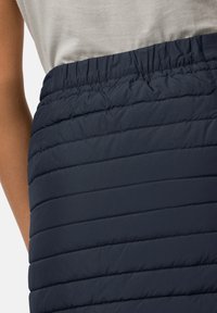 Marineblauwe pufferrok met horizontaal gestikte secties, elastische tailleband en een gladde textuur. Geschikt voor het laagjes dragen in koud weer.