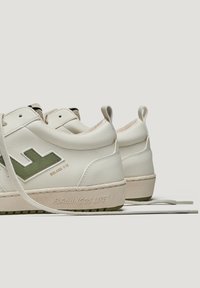 Baskets en cuir blanc avec des accents verts, bout rond, semelle plate et logo en vinyle. Présentent un marquage métallique et des lacets texturés.