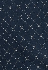 Granatowy materiał z wzorem w siatkę składającym się z białych kropek, o teksturowanej powierzchni i równomiernie rozłożonym geometrycznym wzorze.