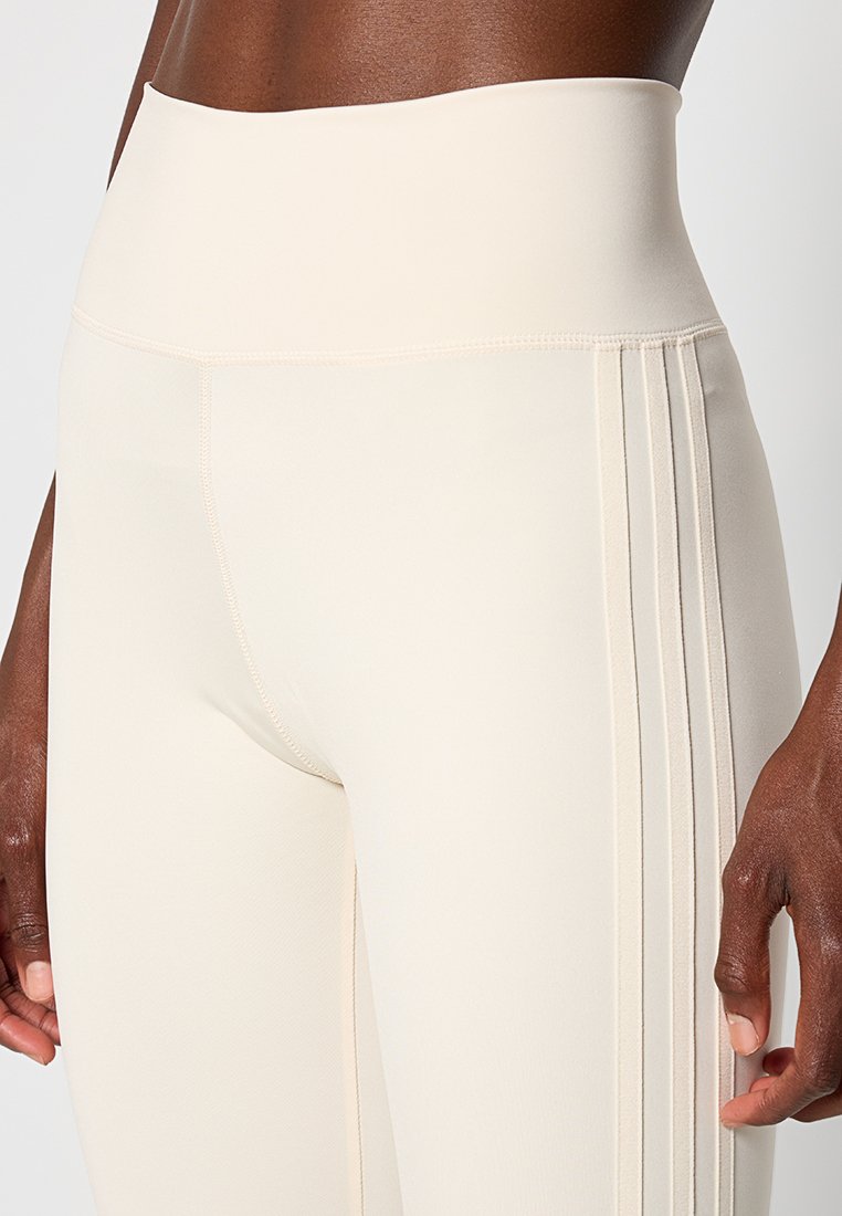 Leggings beige a vita alta con tessuto testurizzato, dotati di cuciture verticali e una finitura liscia. Design elasticizzato e aderente.