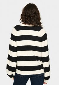 Maglione a righe nero e crema realizzato in maglia con una vestibilità comoda e maniche a palloncino. Caratterizzato da un collo arrotondato e una texture morbida.