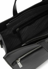 Bolso de mano de cuero negro con un exterior texturizado, cierre de cremallera y un interior que cuenta con un forro estampado y múltiples bolsillos para organización.