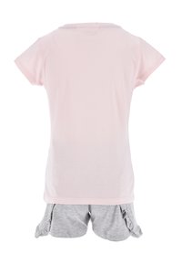 T-shirt rose clair à manches courtes avec un col rond, assorti à un short gris avec des accents volants et une taille élastique.