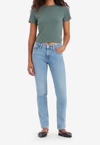 Grön kortärmad t-shirt kombinerad med ljusblå högmidjade jeans, med en klassisk femficksdesign och en ren denimfinish. Svarta balettklänningar.