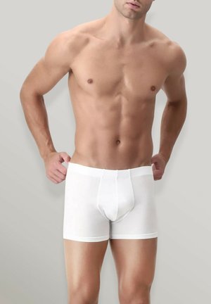 Boxer shorts bianchi in cotone con design aderente, vita elastica e texture liscia, indossati da un modello maschile a petto nudo.