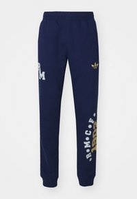 Calças de treino azul marinho com cintura elástica. Apresentam um logotipo dourado da Adidas e padrões de texto em branco, feitas de um tecido suave. Punhos ajustáveis.