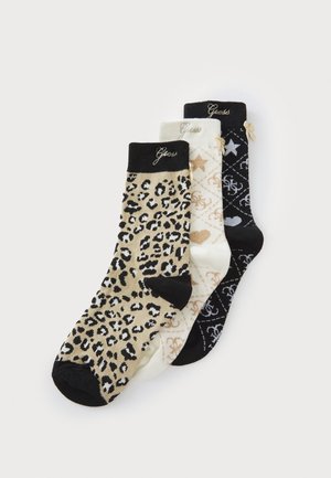 Trois paires de chaussettes de cheville : une avec un motif léopard, une en crème avec des étoiles, et une noire avec un motif logo, toutes avec des bords contrastants.