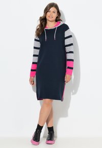 Abito con cappuccio di colore blu navy, maniche a strisce grigie e dettagli rosa. Il tessuto sembra morbido; il design presenta delle aperture laterali per una maggiore libertà di movimento.