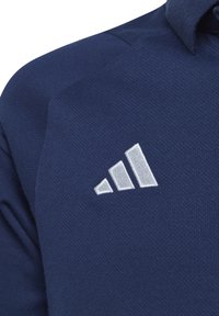 Marineblauwe polo met een gestructureerde stof, voorzien van een opvallend wit geborduurd logo met drie oplopende strepen op de linkerborst.