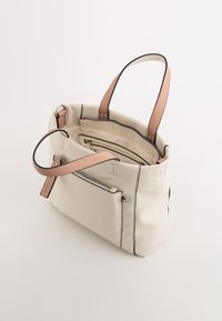 Kremowa torba tote z ekoskórki z kontrastującymi czarnymi wykończeniami, dwiema brązowymi rączkami oraz wnętrzem z kieszenią na zamek. Przestronny design i gładka tekstura.