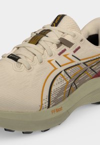 Κοντινό πλάνο μπεζ αθλητικού παπουτσιού Asics με πορτοκαλί και μαύρες λεπτομέρειες, επάνω μέρος από δίχτυ, ετικέτα Gore-Tex και απορροφητική σόλα FF Blast.