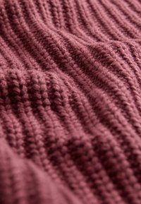 Burgunderfarbener Strickstoff mit einem strukturierten Rippmuster, das dickes Garn und eine weiche, flauschige Oberfläche zeigt.