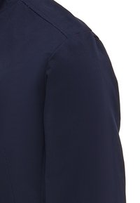 Dettagli in tessuto blu navy con una trama liscia, caratterizzati da una cucitura sulla spalla e un taglio strutturato senza chiusure o decorazioni visibili.