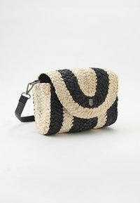 Borsa intrecciata in crema e nero con una patta curva, caratterizzata da una texture intrecciata e un logo metallico in evidenza, completata da una tracolla removibile.