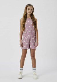 Rosa ærmeløs jumpsuit med hvidt hjerte mønster, elastisk talje og korte ben. Kombineret med stribede sokker og hvide sneakers.