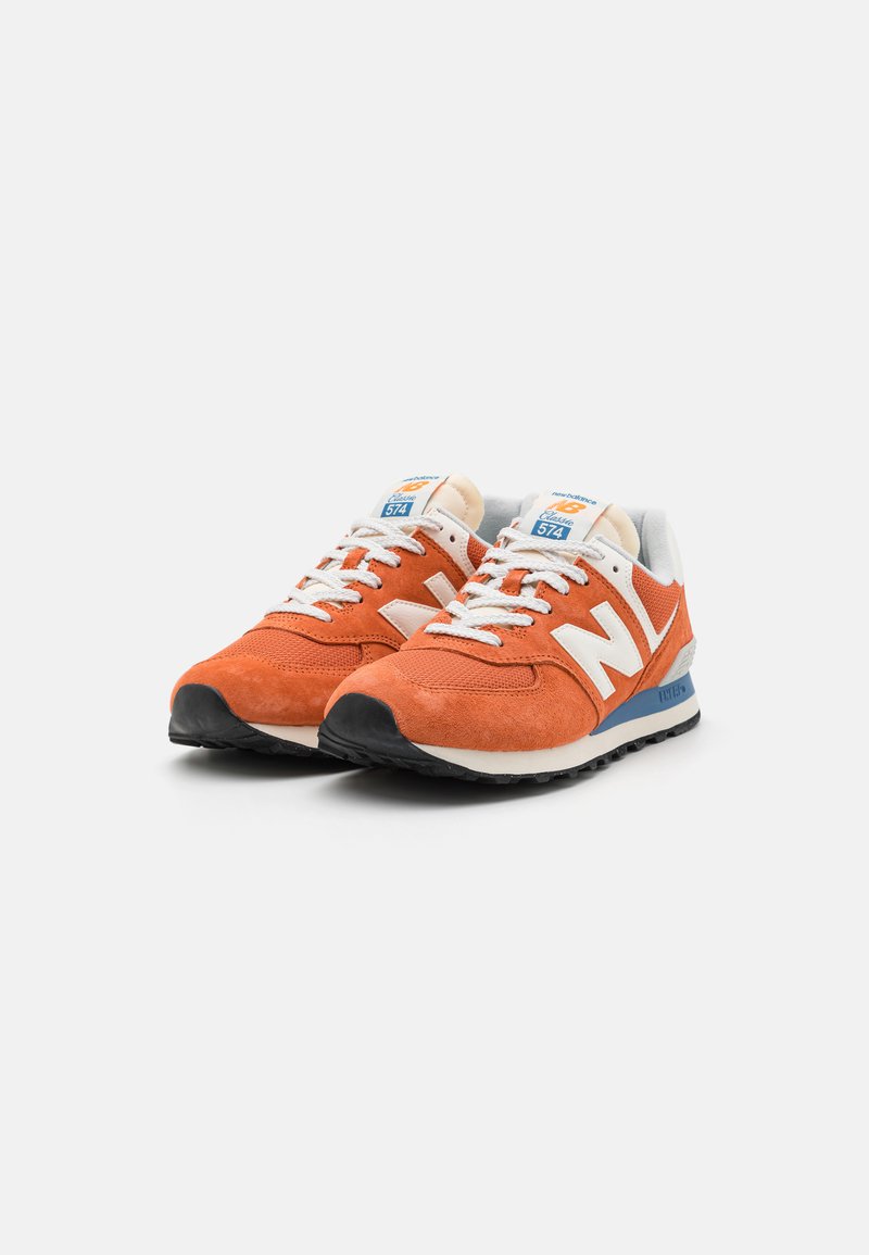 Baskets en suede orange avec des panneaux en maille, des accents blancs et des détails bleus. Présentent des lacets plats et une semelle en caoutchouc noir texturé.