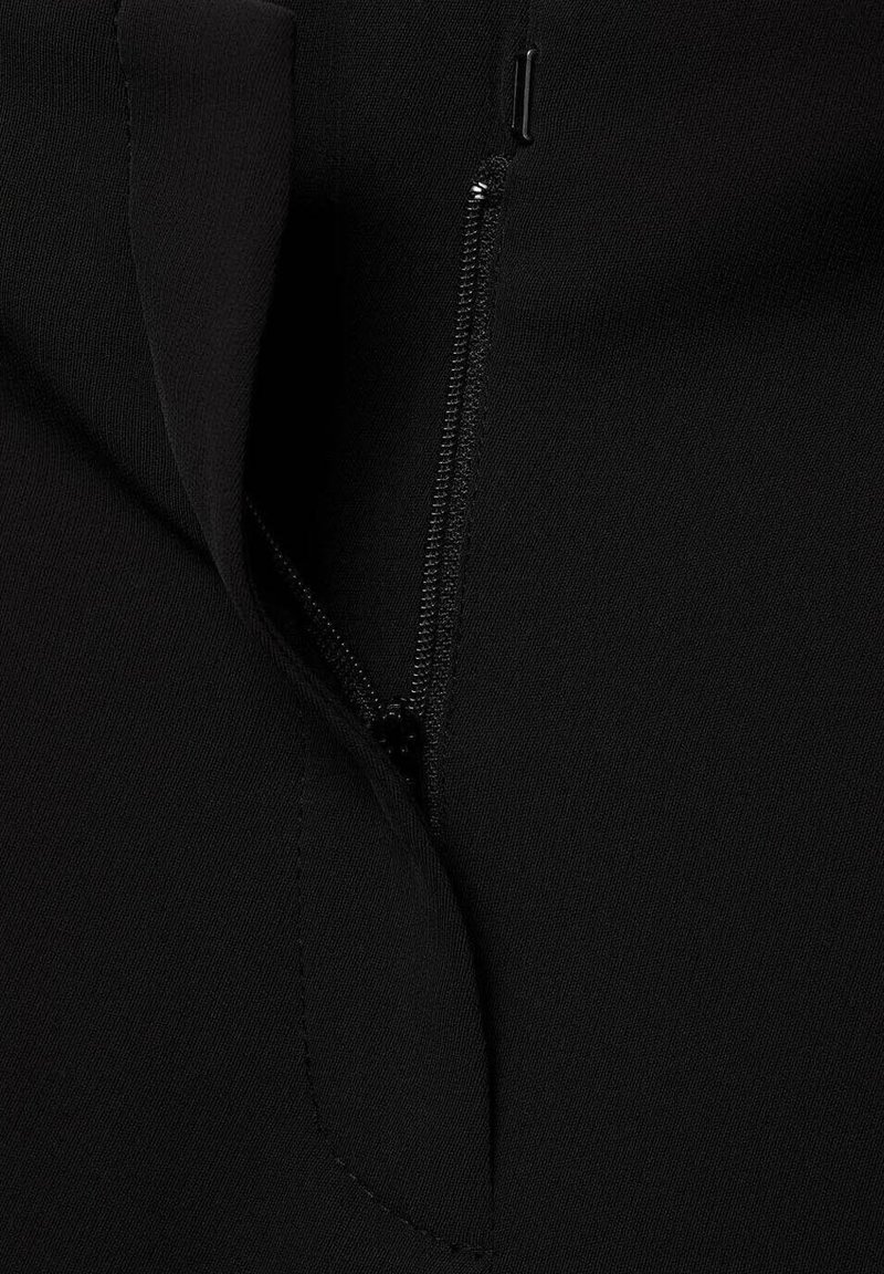 Prenda negra con un detalle de cremallera oculta a lo largo de la costura lateral, con una textura suave y un acabado bien cosido.