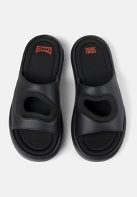 Zwarte schuifslippers met synthetisch bovenmateriaal, voorzien van twee ronde uitsparingen en een gevoerde zwarte stoffen voering. Camper merklogo bovenop.