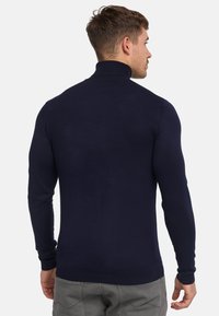 Navyblauwe coltrui met lange mouwen, ribbelstructuur en een slimfit ontwerp. Gemaakt van een zachte, rekbare stof.