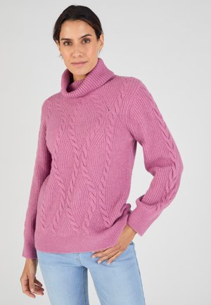 Maglione rosa lavorato a maglia con collo a barchetta, maniche lunghe e un motivo testurizzato. Presenta una vestibilità comoda e orlo a coste. Abbinato a jeans azzurri chiari.