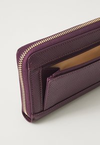 Lilla tekstuuriga rahakott kuldse lukuga, millel on mitmed kaardipesad ja väike lukuga compartment sees. Sile sisemine vooder.