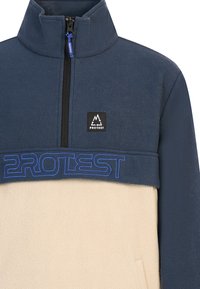 Fleece-Pullover in marineblau und creme, mit Reißverschlusskragen, featuring blauer gestickter "PROTEST"-Schriftzug und Logo-Patch auf der Brust. Weiche Textur.