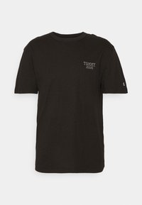 T-shirt en coton noir avec un col rond, des manches courtes et un petit logo blanc "TOMMY JEANS" sur la poitrine gauche. Texture lisse.