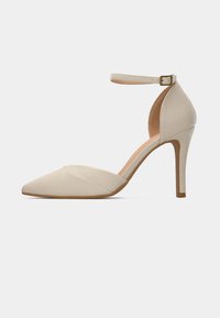 Beige högklackad sko med spetsig tå, ankelsnodd och slät tyg. Har en smal klack och en minimalistisk design.