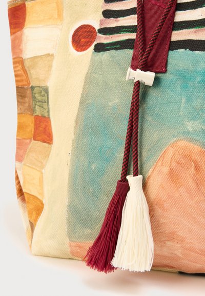 Τσάντα tote από καμβά με αφηρημένα πολύχρωμα μοτίβα. Διαθέτει φούντες σε μπορντό και εκρού, υφή στην επιφάνεια και ασφαλές κλείσιμο.