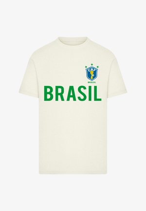 Balts kokvilnas T-krekls ar zaļu tekstu "BRASIL" un zilu emblēmu ar kausu un zvaigznēm virsū, kas atrodas kreisajā krūtīs.