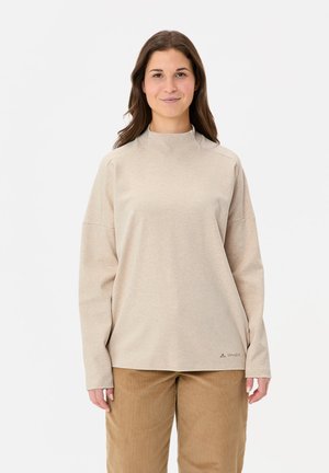 Beige long-sleeve top with a high neckline, relaxed fit, and raglan sleeves. Features subtle logo detail near the hem and soft texture.