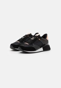 Scarpe da ginnastica nere con un design misto di materiali che combina rete e suede, accenti testurizzati, intersuola bianca e suola in gomma nera.