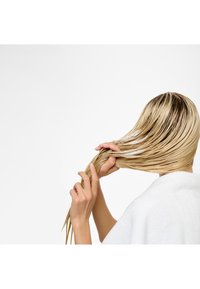 Blond haar in natte strengen wordt met handen vastgehouden. De persoon draagt een witte handdoek, met de nadruk op de haartextuur en lengte.