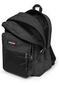 Zaino Eastpak nero con una finitura testurizzata e luccicante. Presenta doppie cerniere, una tasca frontale in rete e spallacci imbottiti per il massimo comfort.