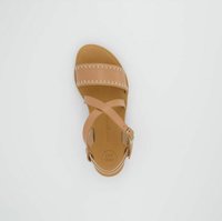 Sandale en cuir tan avec des lanières croisées et des coutures blanches. Semelle plate avec une semelle intérieure de marque. Bretelle de cheville ajustable avec une boucle dorée.