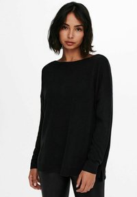 Pull en maille noir à coupe ample, avec un décolleté large et des accents côtelés, présentant des fentes latérales et des manches longues pour un look décontracté.