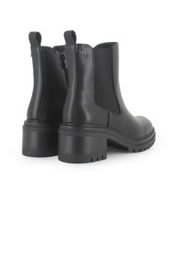Botines negros de tobillo con un acabado de cuero suave, paneles laterales elásticos y un tacón grueso. Presentan una lengüeta y una suela con tracción para un mejor agarre.
