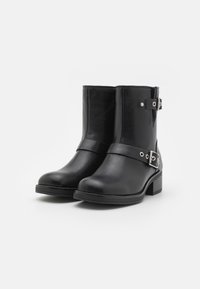 Czarne skórzane botki za kostkę o gładkiej fakturze, z detalem w postaci pasków z klamrą i niskim obcasem w kształcie bloku.