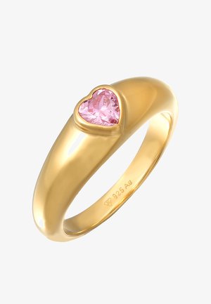 Anillo de metal color dorado con una montaura de gema rosa en forma de corazón, superficie lisa y acabado pulido, con una talla marcada en el interior.