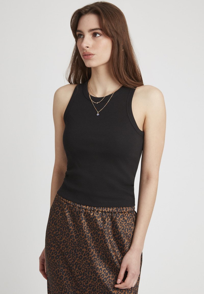 Top noir à rayures avec un design sans manches, associé à une jupe à imprimé léopard brun. La tenue présente une silhouette ajustée et une texture lisse.