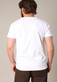 Witte katoenen T-shirt met een ronde hals en korte mouwen, weergegeven vanuit de achterkant, met een zachte textuur en een relaxte pasvorm.