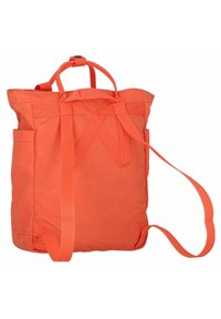 Sac fourre-tout en tissu orange avec deux poignées supérieures, bandoulière ajustable, poche extérieure et coutures renforcées sur les anses.