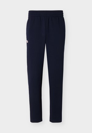 Tengerészkék slim fit melegítők, elasztikus derékpánttal és kis hímzett logóval a bal csípőn, fehér háttéren laposan elhelyezve.