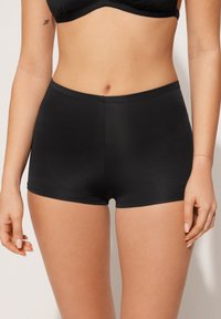 Černé hipsterské šortky vyrobené z hladkého, elastického materiálu, s bezešvým designem a decentním pokrytím. Ozdobené čistým, minimalistickým vzhledem.