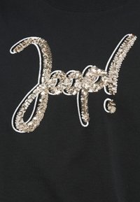 Μαύρο πουκάμισο με μεγάλο λογότυπο "Jeep!" από χρυσά παγιέτες, με περίγραμμα από λευκή κλωστή, και υφή ομαλού υφάσματος.