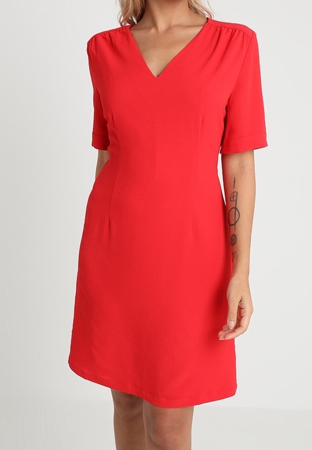 Röd klänning med korta ärmar och V-ringning, tillverkad av lätt tyg. Har en figursydd midja och subtil veckning vid axlarna.