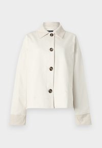 Chemise à manches longues blanc cassé avec boutons foncés et col pointu sur fond uni.